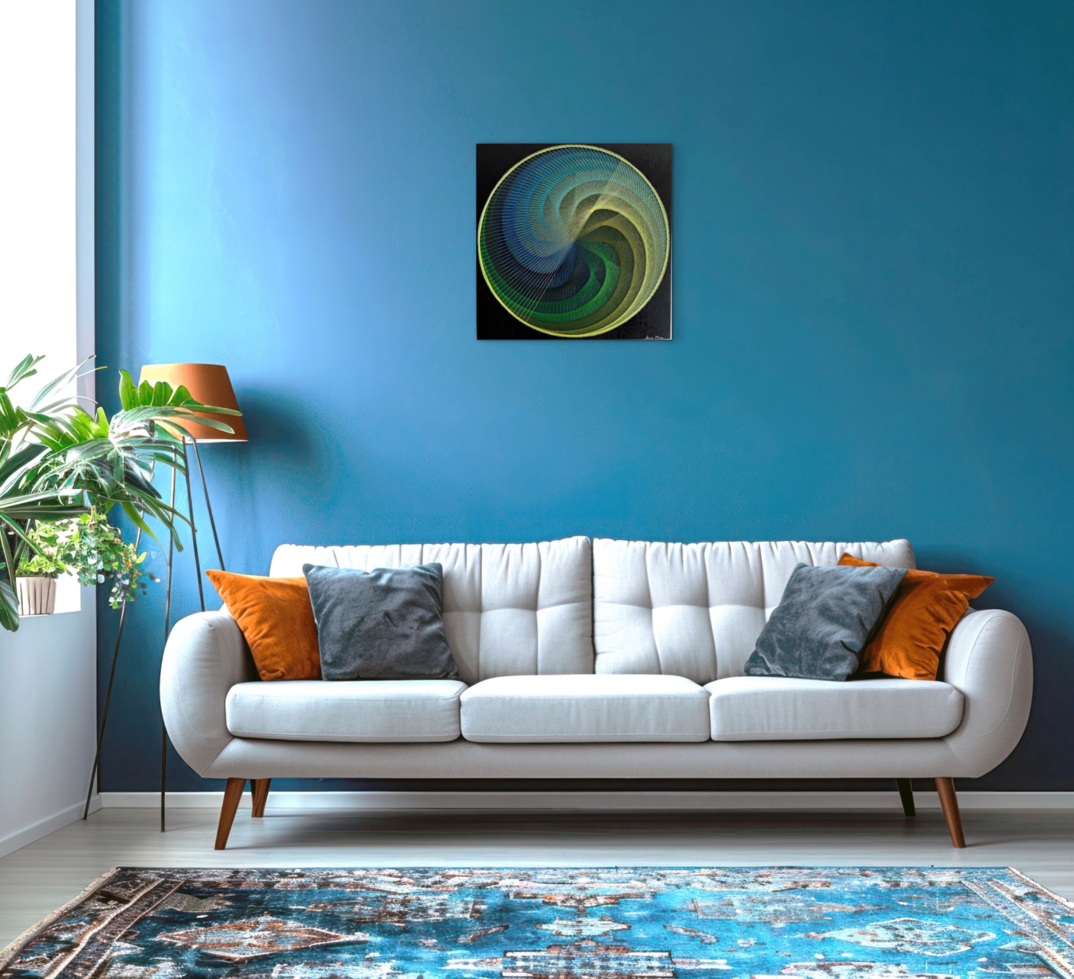 Blue and green spiral string art displayed above a white sofa on a deep blue wall